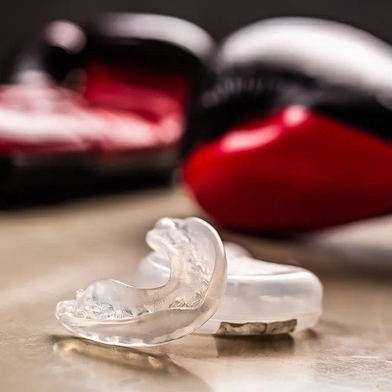 Image of a sports guard on the ground with boxing gloves in the background