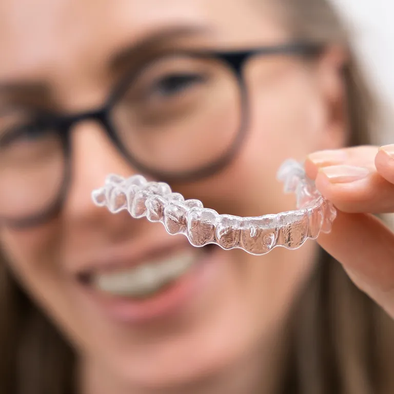 Image of a woman holding invisalign braces