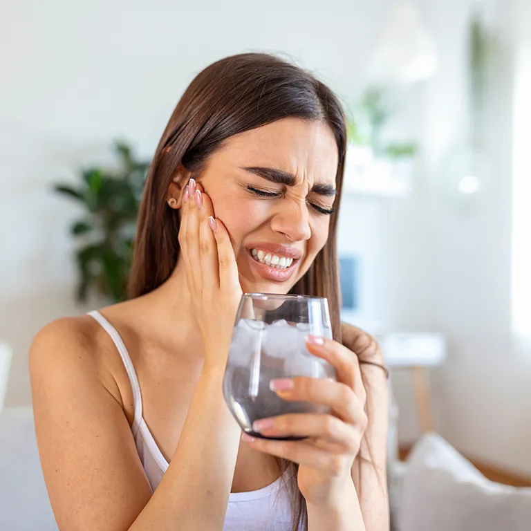 Image of a woman in pain holding glass of water